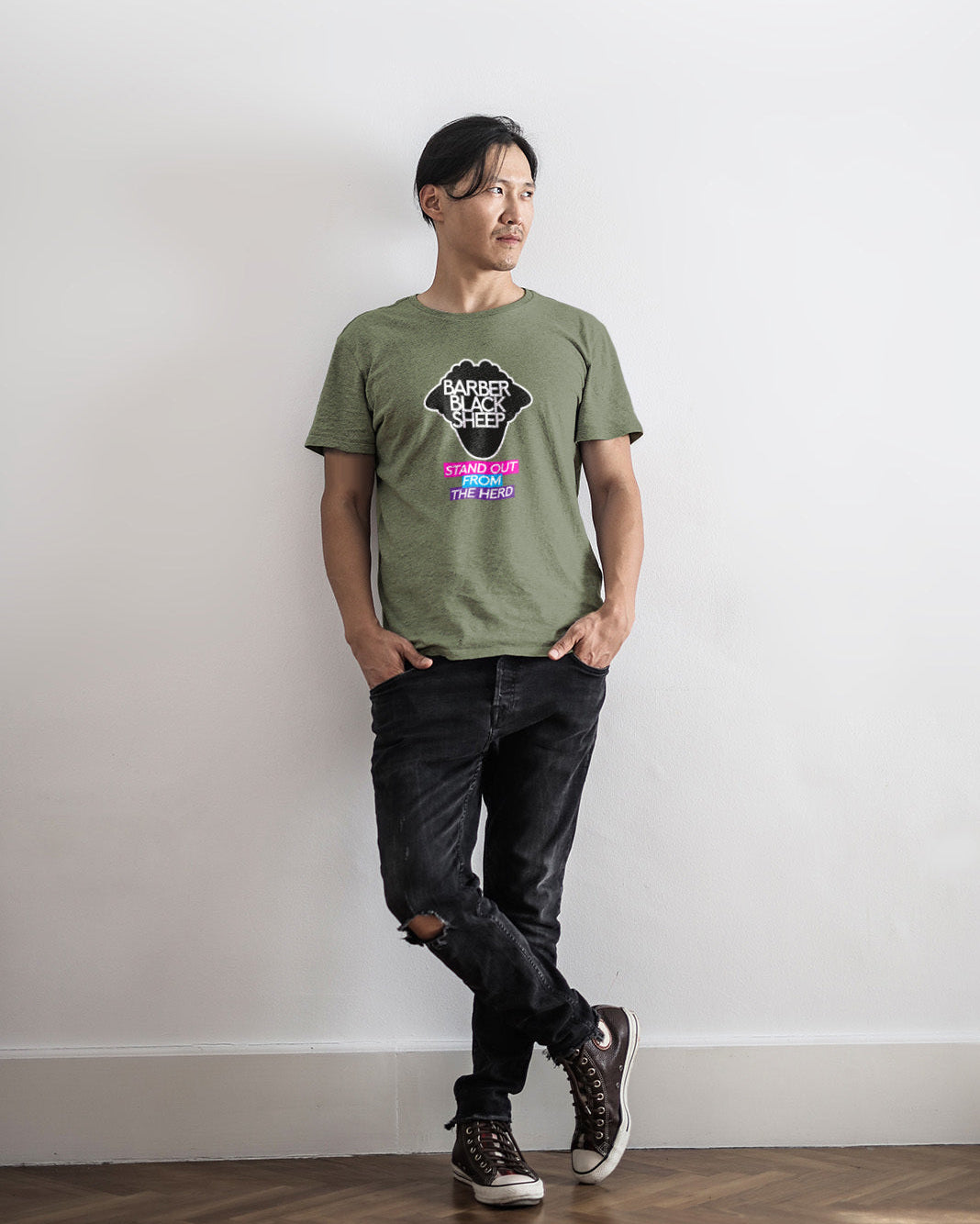 Person wearing a green t-shirt with a graphic design against a white wall.