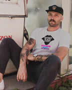 Man sitting on a step wearing a t-shirt with a graphic design, in front of a gas pump.