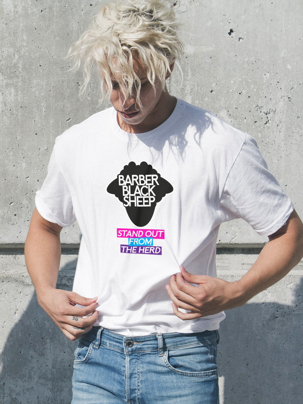 Person wearing a white t-shirt with a graphic design and text, standing against a concrete wall.